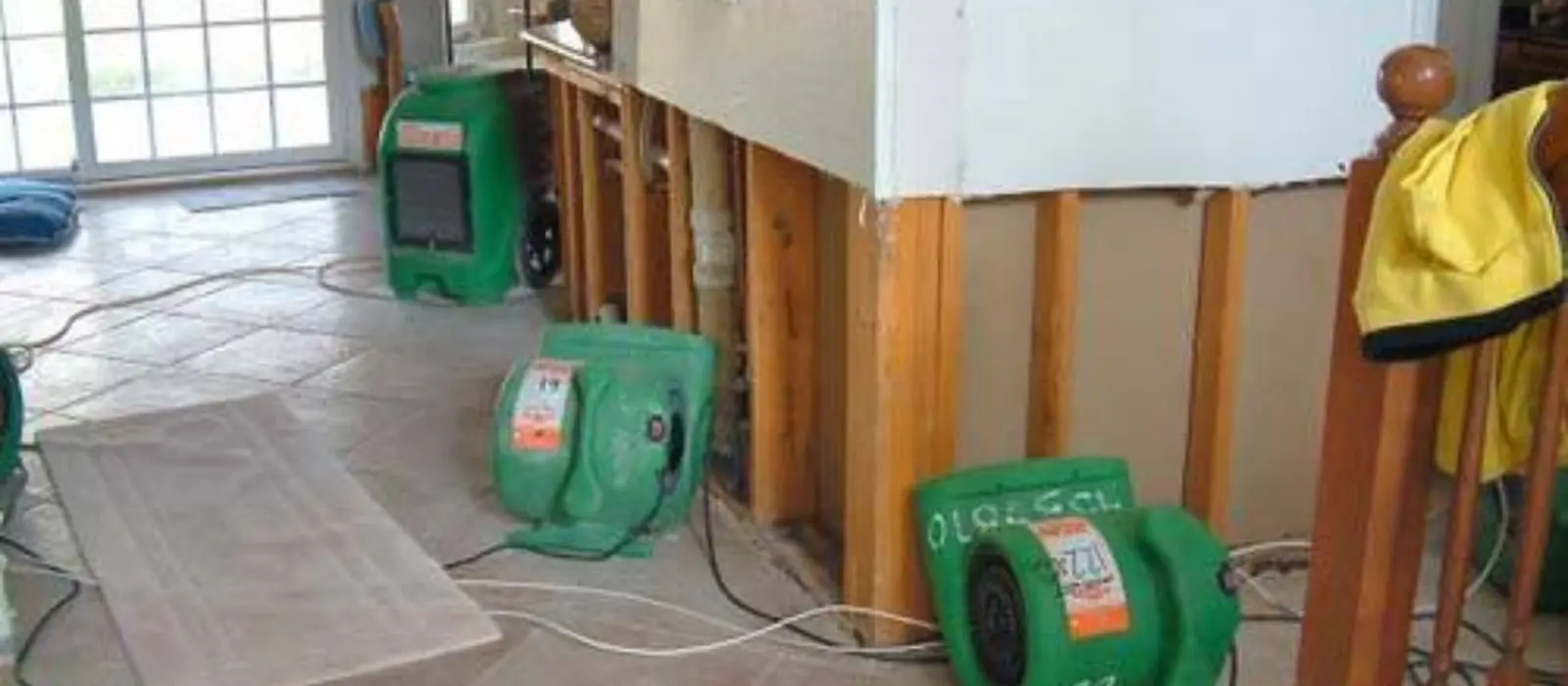 Wet drywall cut out near the floor with air movers drying the room
