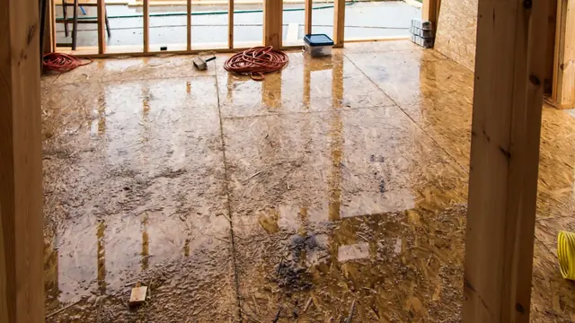 Warped hardwood boards on a wet floor in a room being renovated