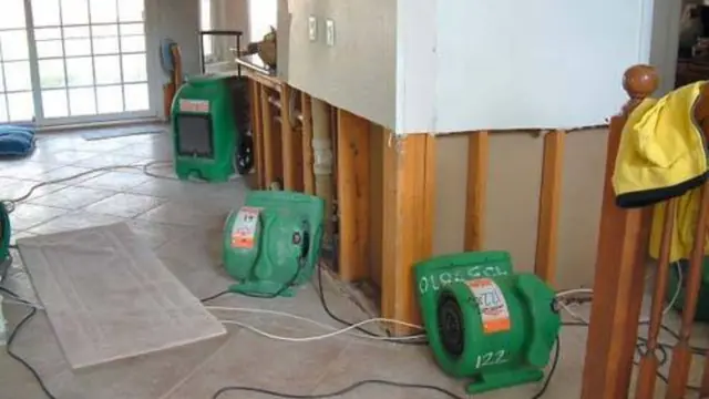 Wet drywall cut out near the floor with air movers drying the room