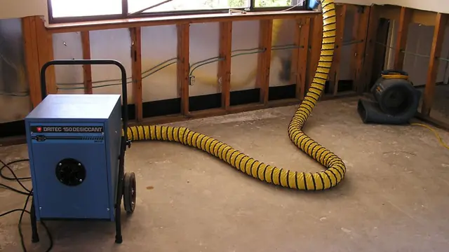 Dehumidifier and a yellow duct hose running beside opened walls